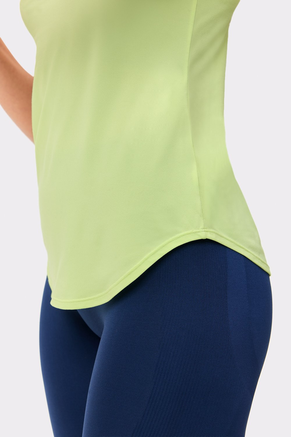 Nahaufnahme des limegrünen Airy Racerback Tank von Stronger, die den abgerundeten Saum und die entspannte Passform zeigt.
