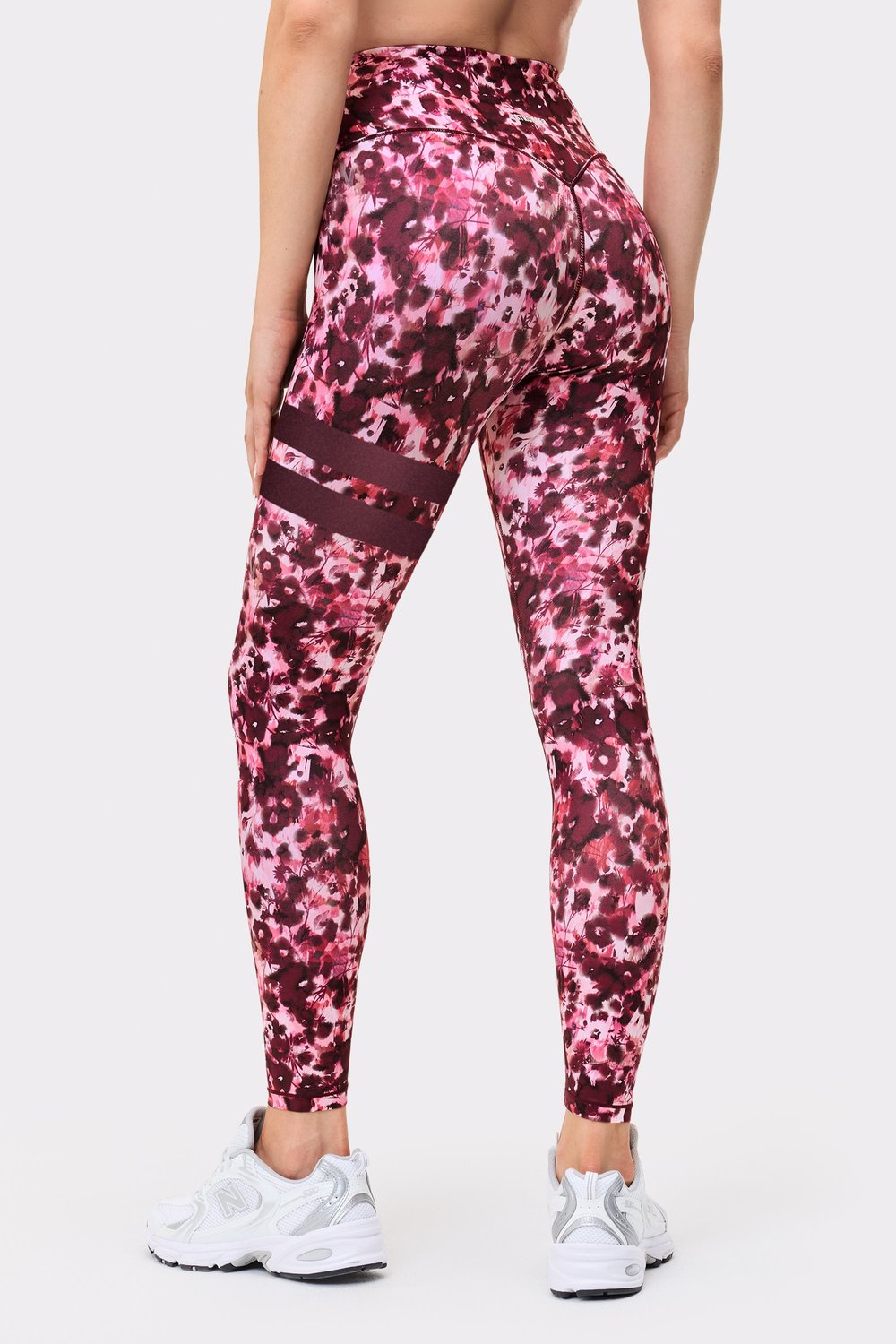 Back view of a woman wearing the Stronger Signature One Leggings in Autumn Petals, showing the signature lines on the leg.