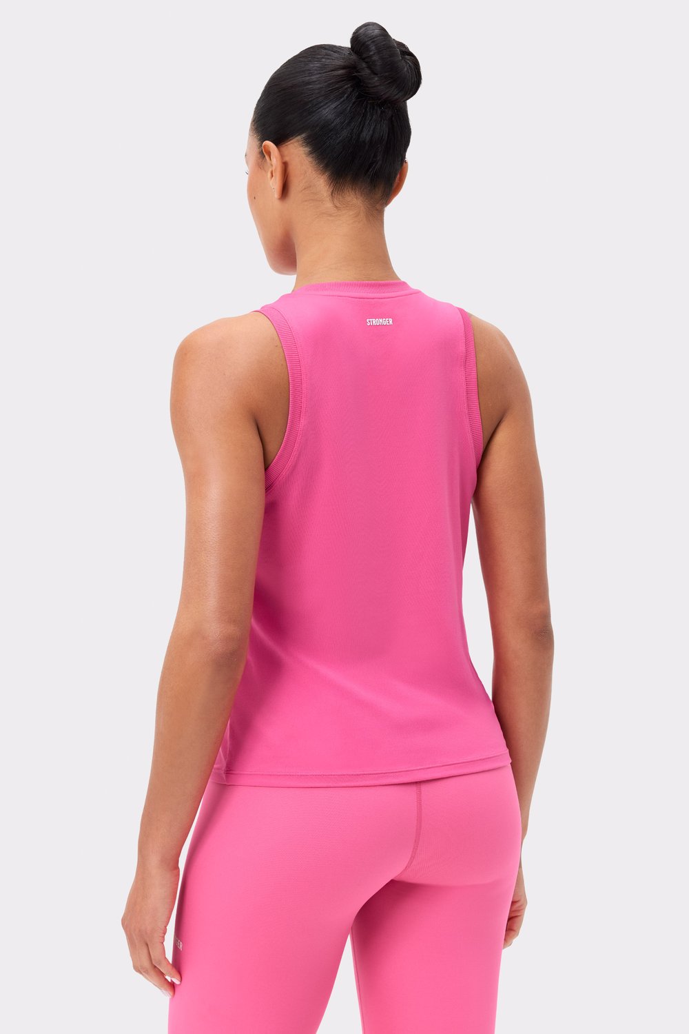 Back view of the pink Stronger Relaxed Tank, featuring ribbed details and a small logo at the back neck.