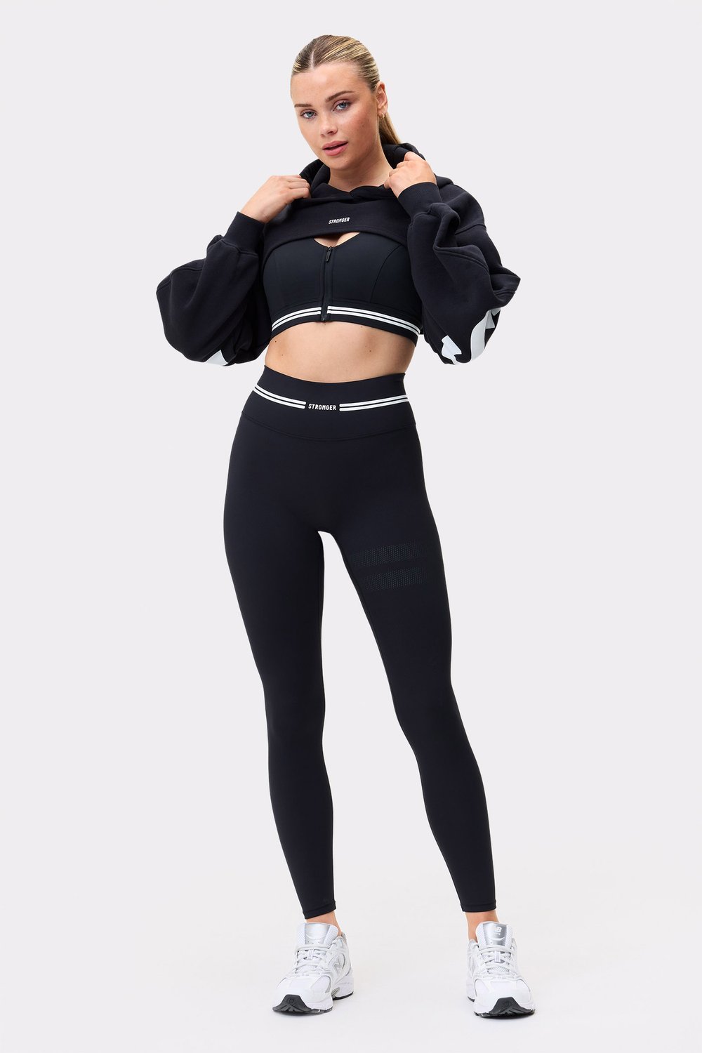 Model in schwarzem Cropped Hoodie von Stronger mit Oversized-Passform, Bolero-Stil und langen Ärmeln.