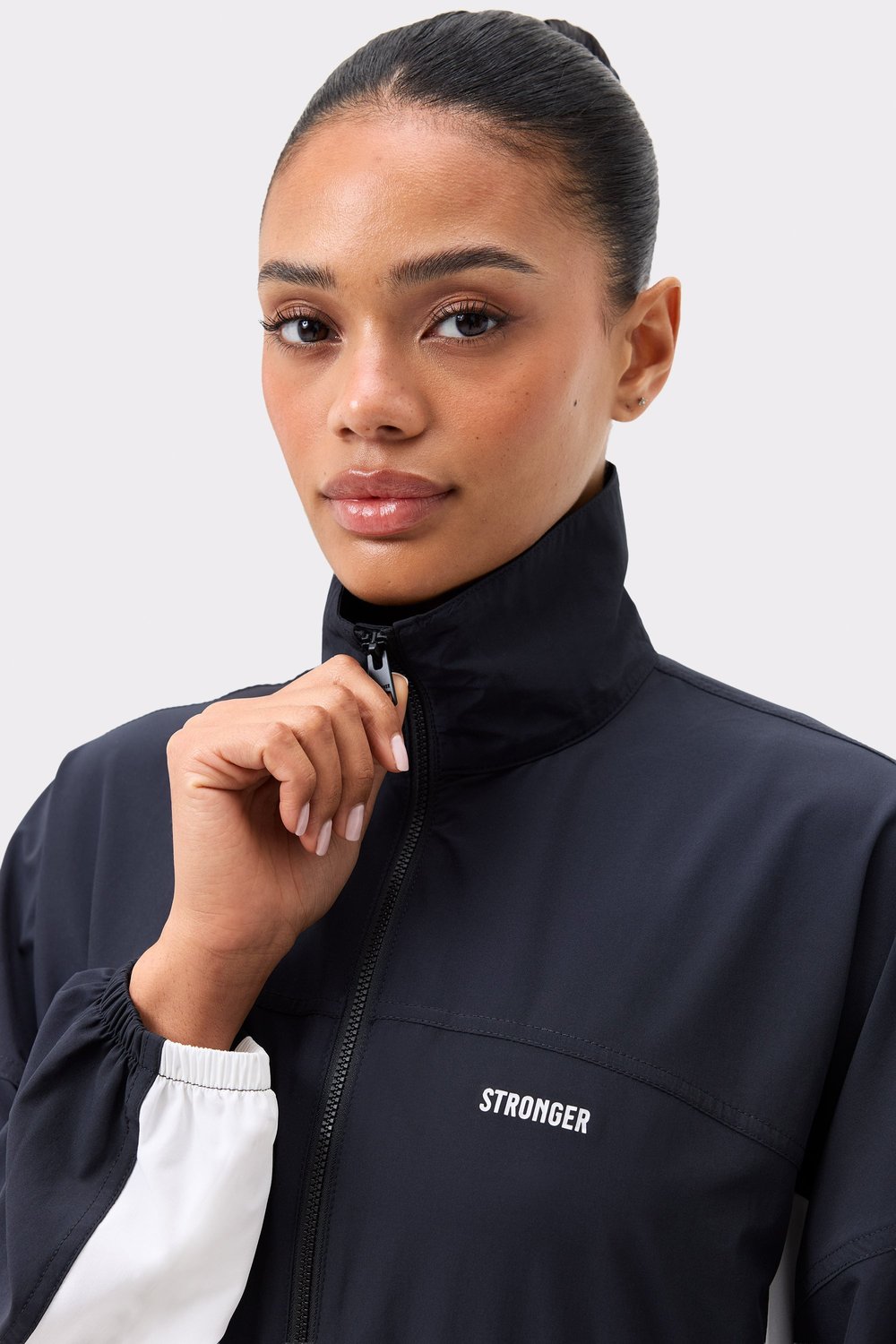 Close-up of Stronger's black Breezy Woven Jacket, featuring a high collar, front zipper, and white cuff detail.