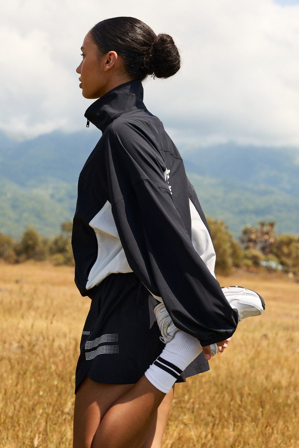 Side view of Stronger's black and white Breezy Woven Jacket, a breathable recycled polyester layer for outdoor wear.