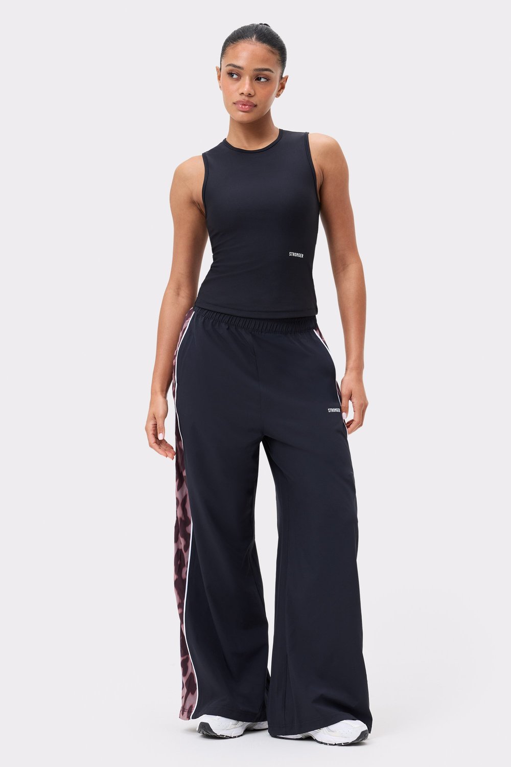Stronger Breezy Woven Pants in Black/Leo Rush met roze luipaard zijpanelen, witte bies, losse pasvorm en hoge taille.
