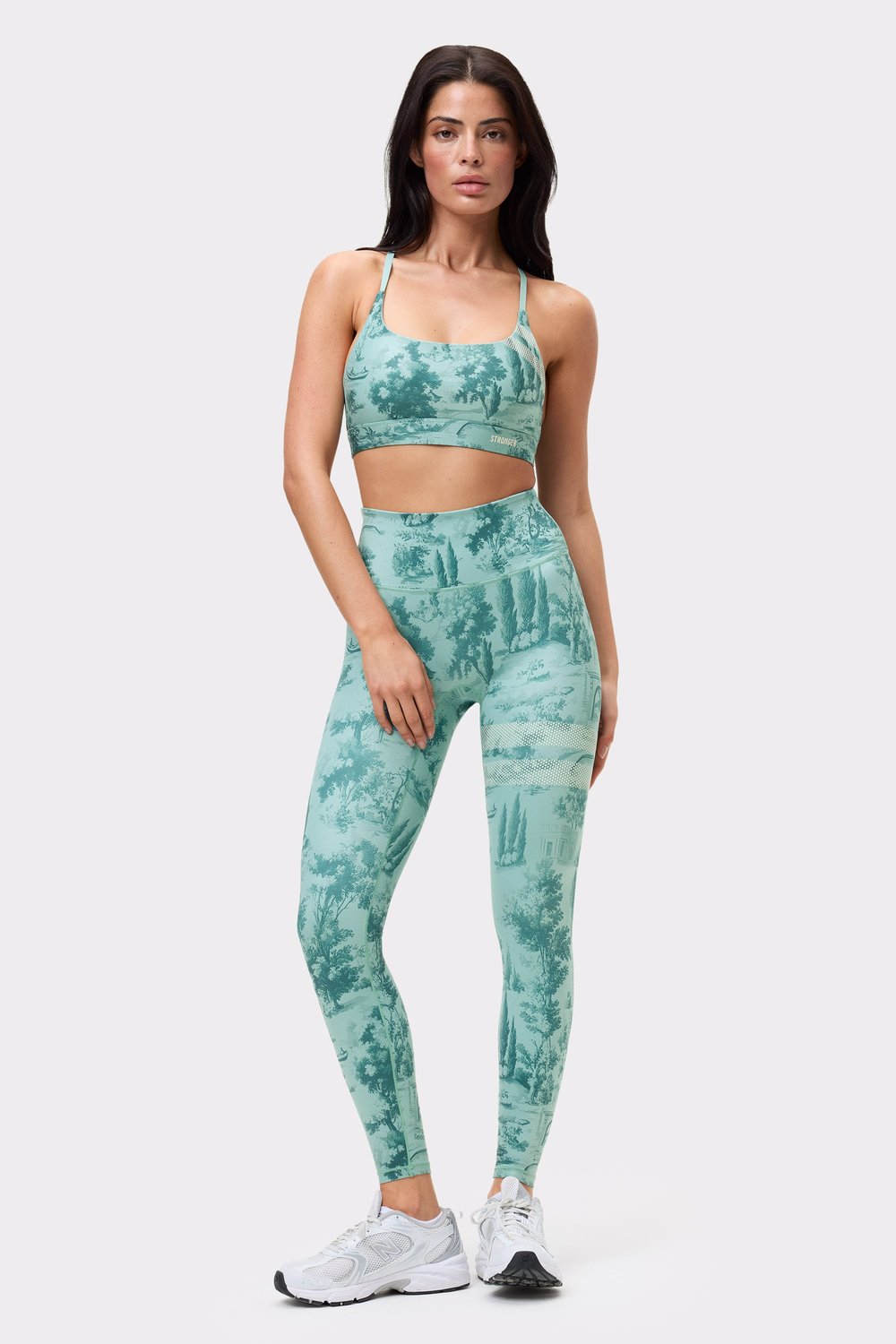 Vorderansicht eines Models im Signature Printed Strap Sports Bra und passenden Leggings mit hellblauem Toile di Roma-Print.