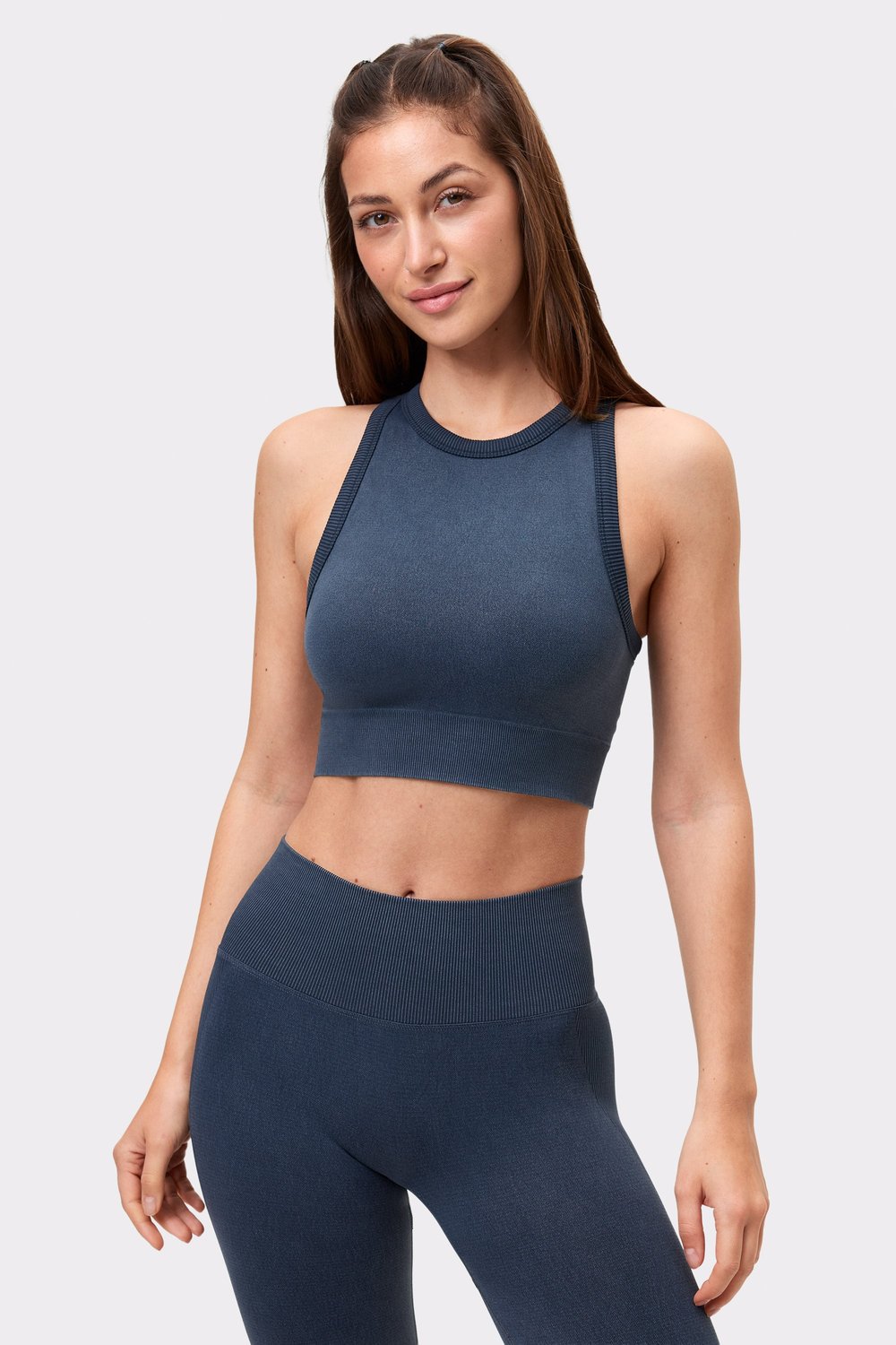 Vorderansicht eines Models im schwarzen Washed seamless high neck bra von Stronger, Teil eines passenden Workout-Sets.