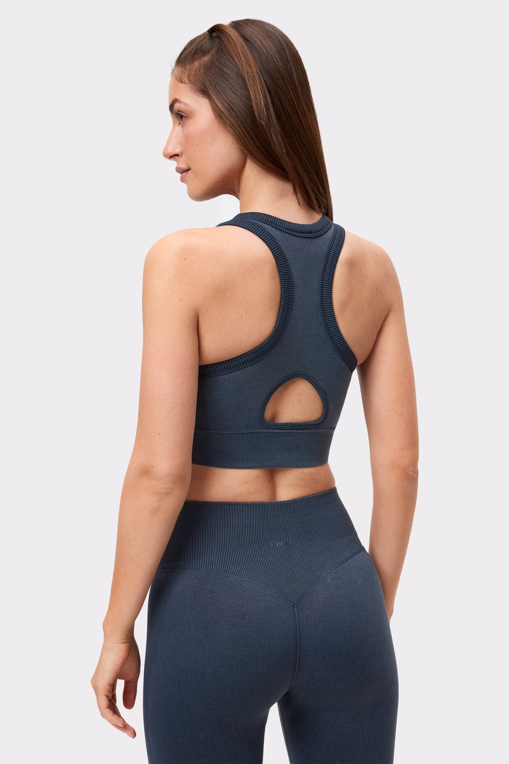 Rückansicht einer Frau mit dem schwarzen Washed seamless high neck bra von Stronger mit Racerback und Keyhole-Detail.