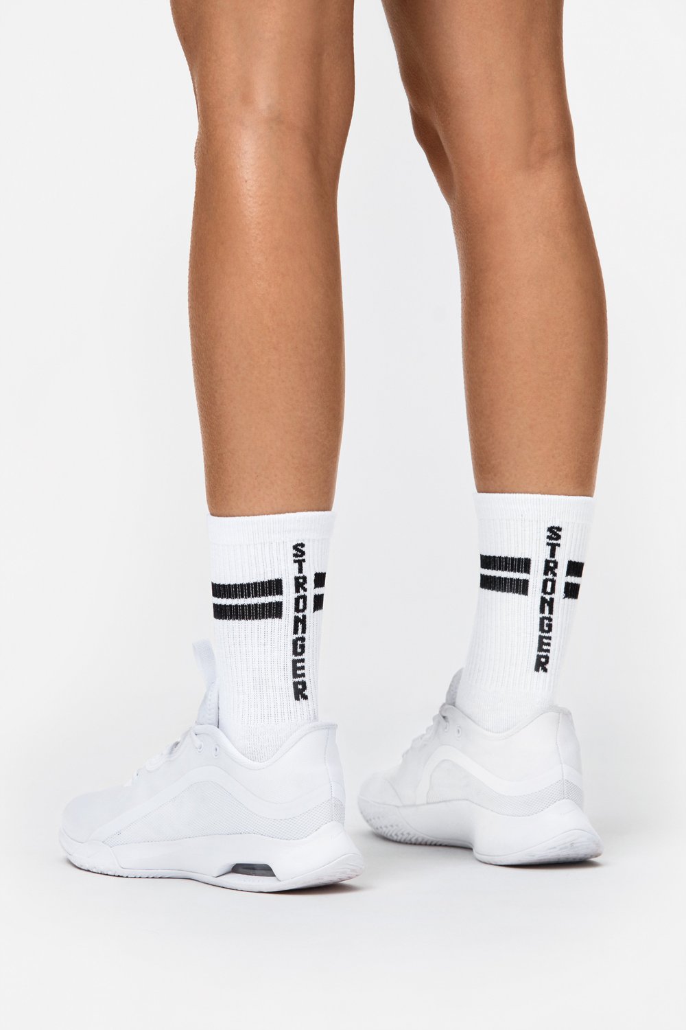 Rückansicht der weißen Stride Socks von Stronger mit schwarzen Signature Lines und Branding, getragen mit weißen Sneakern.