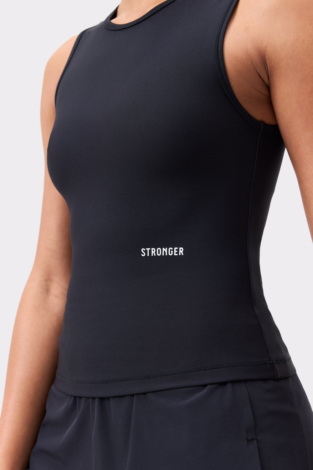Close-up of the black Signature Slim Tank Top by Stronger, featuring the white logo and breathable performance fabric.