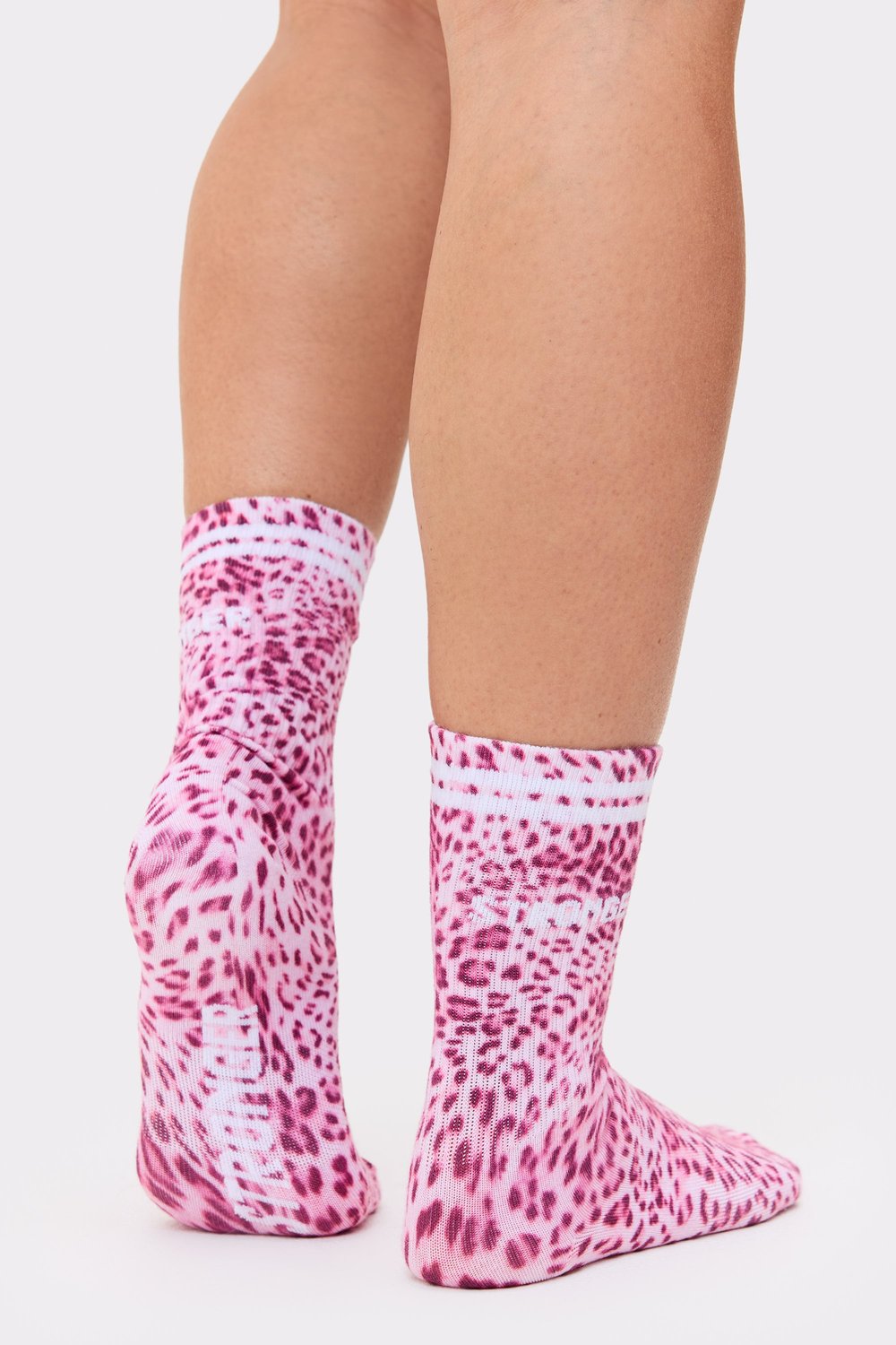 Close-up of a person wearing the pink leo Essential Socks from Stronger with signature stripes at the top.