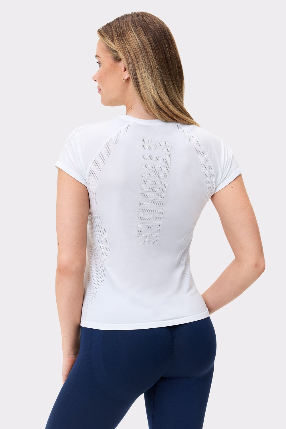 Back view of Stronger's white Seamless Performance T-shirt, featuring a vertical logo and breathable mesh panels.