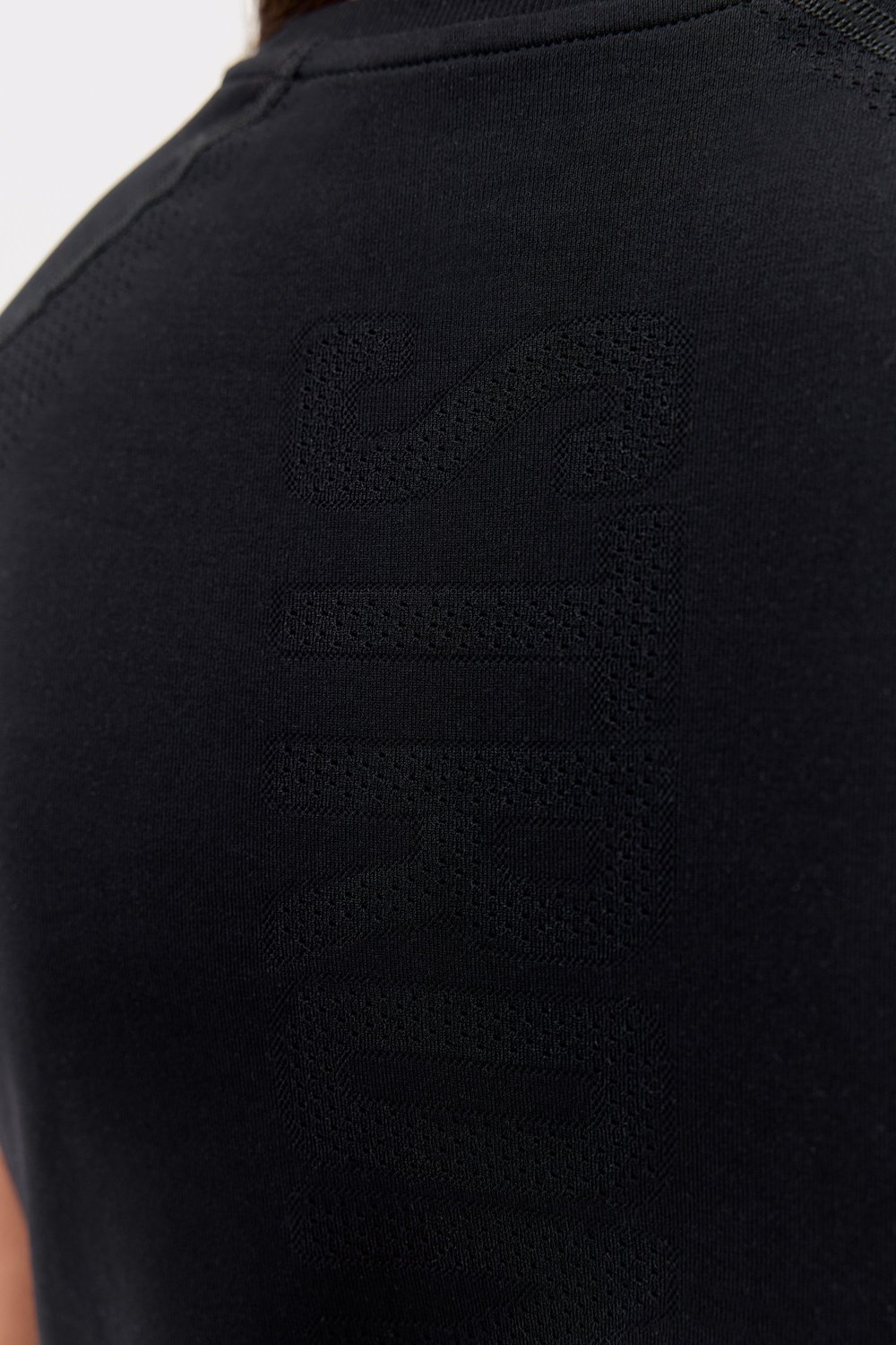 Close-up of the black Stronger Seamless Performance T-shirt, featuring the tonal knitted logo and breathable fabric.