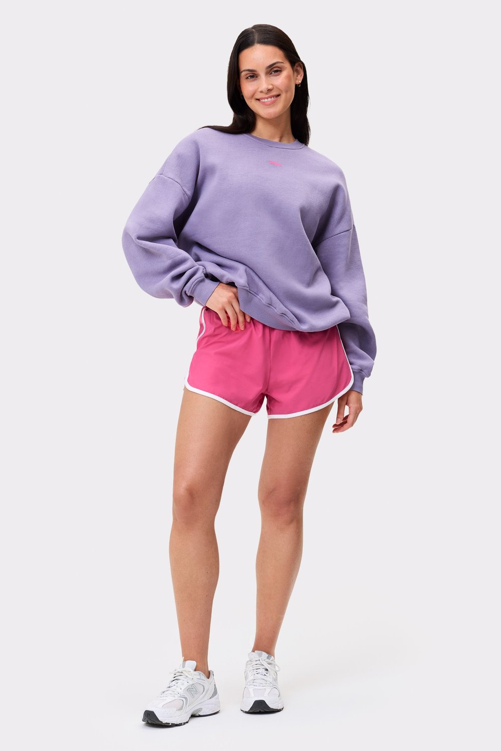 Stronger's oversized Comfy Washed Sweatshirt in Vintage Violet with a washed out look, paired with pink shorts.