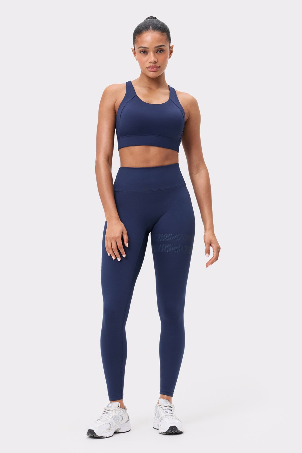 Model in dunkelblauem Bounce Sports Bra von Stronger mit passenden Leggings, für hohen Halt beim Workout.