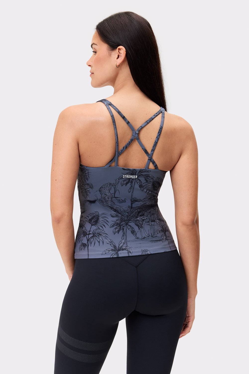 Modell trägt das schmale, verkürzte Stronger Signature Strappy Tank im Dark Toile-Print mit Trägerdetails am Rücken.