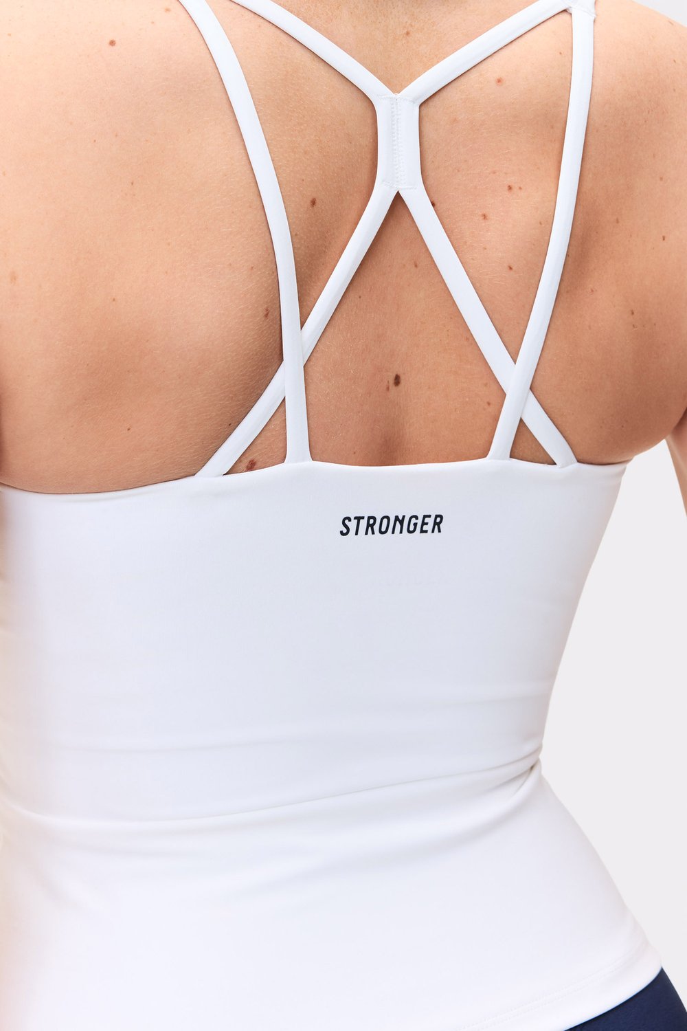 Rückansicht des weißen Signature Strappy Tank von Stronger, die die Trägerdetails und das zentrierte Logo hervorhebt.