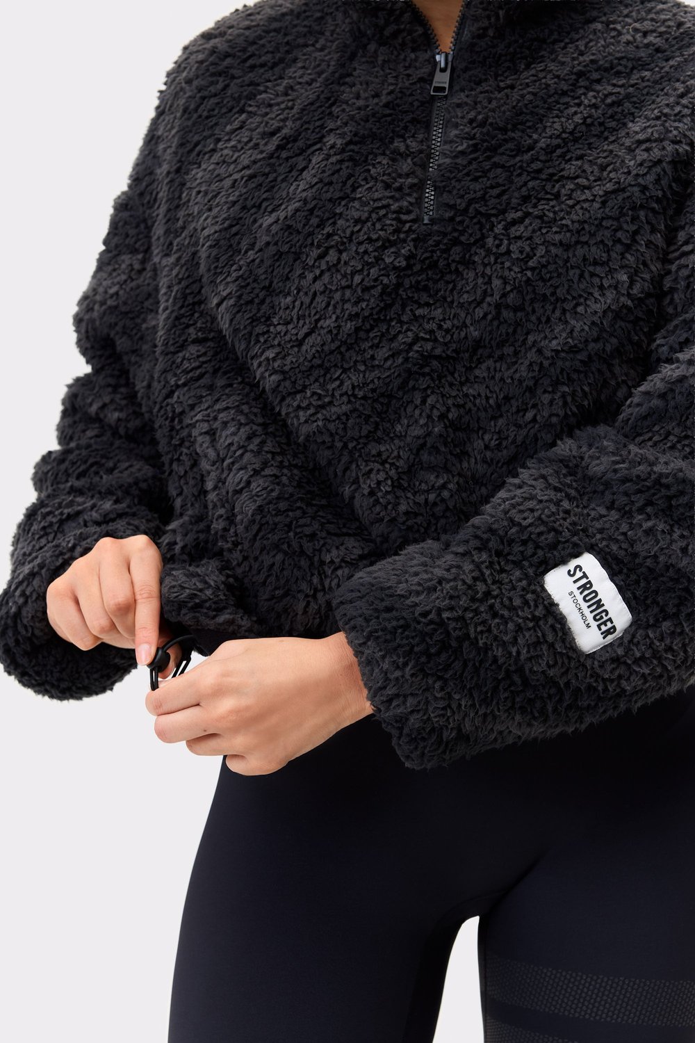 Nahaufnahme der Stronger Pile Half Zip Jacket in Black Zebra mit kuscheliger Fleecetextur und verstellbarem Saum.