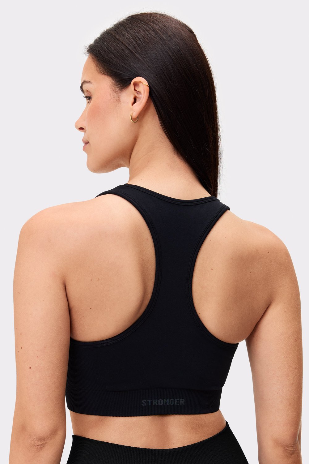 Rückansicht eines Models im schwarzen Seamless Contour Sports Bra von Stronger mit überkreuztem Design.