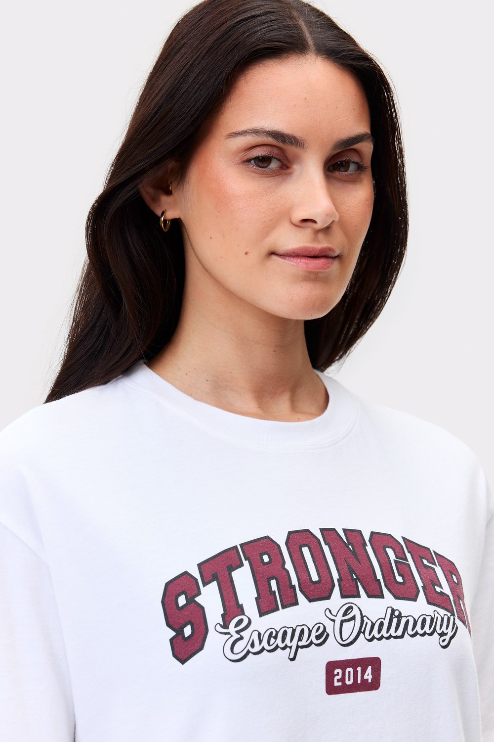 Model trägt das weiße Essential T-shirt von Stronger mit regulärer Passform und gedruckter Grafik mittig auf der Vorderseite.