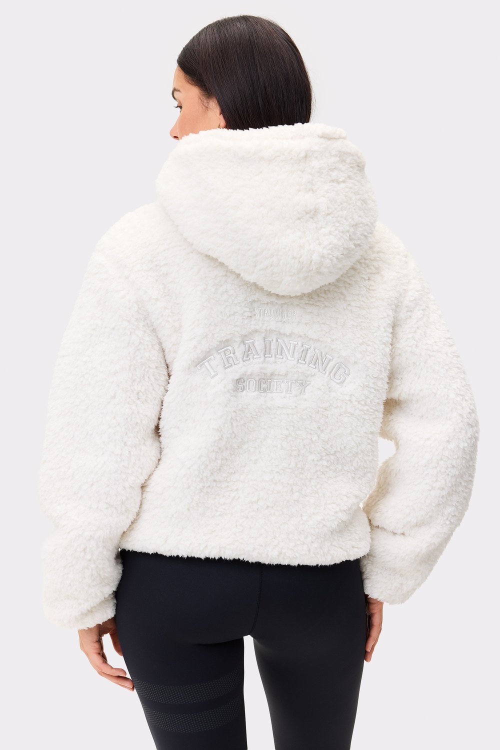 Rückansicht einer Person in der weißen Hooded Pile Jacket von Stronger mit kuscheligem Teddy-Fleece und Stickerei am Rücken.