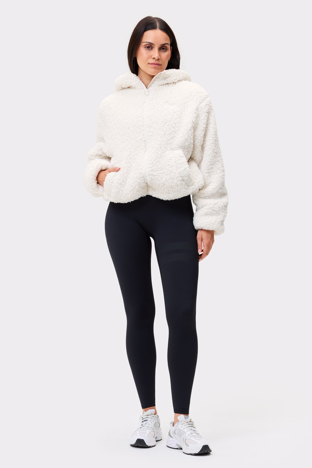 Model trägt die weiße Hooded Pile Jacket von Stronger aus recyceltem Polyester für gemütliche Freizeitkleidung.