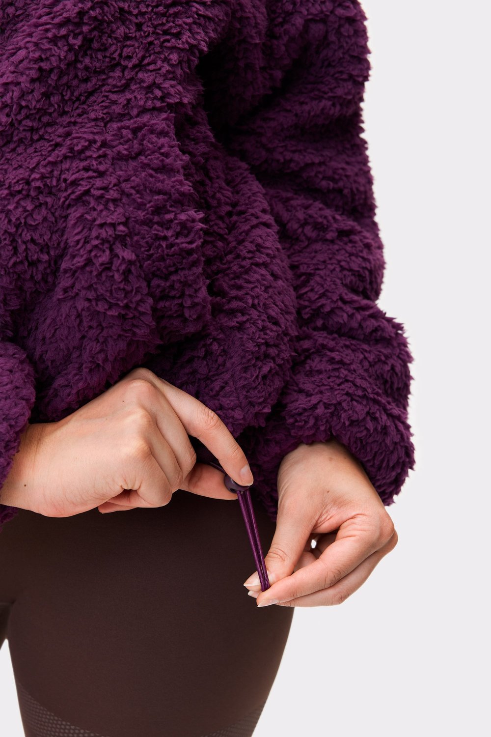 Close-up of the hem adjustment detail on the dark purple Hooded Pile Jacket from stronger.