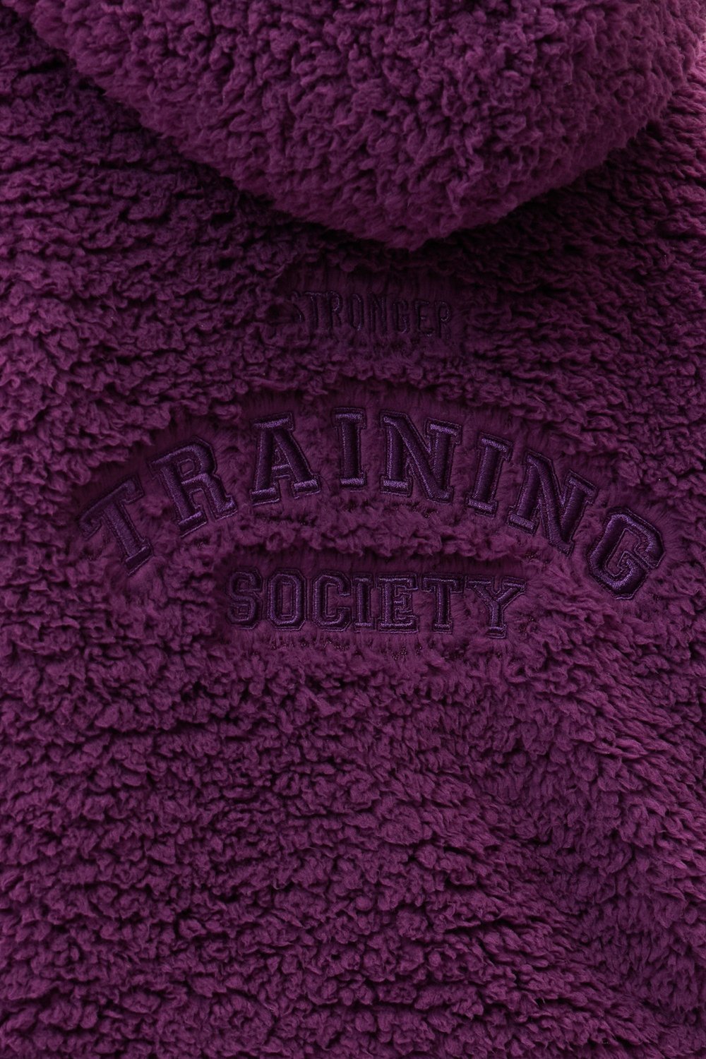 Close-up of the dark purple Hooded Pile Jacket by stronger, showing the embroidered back graphic details.