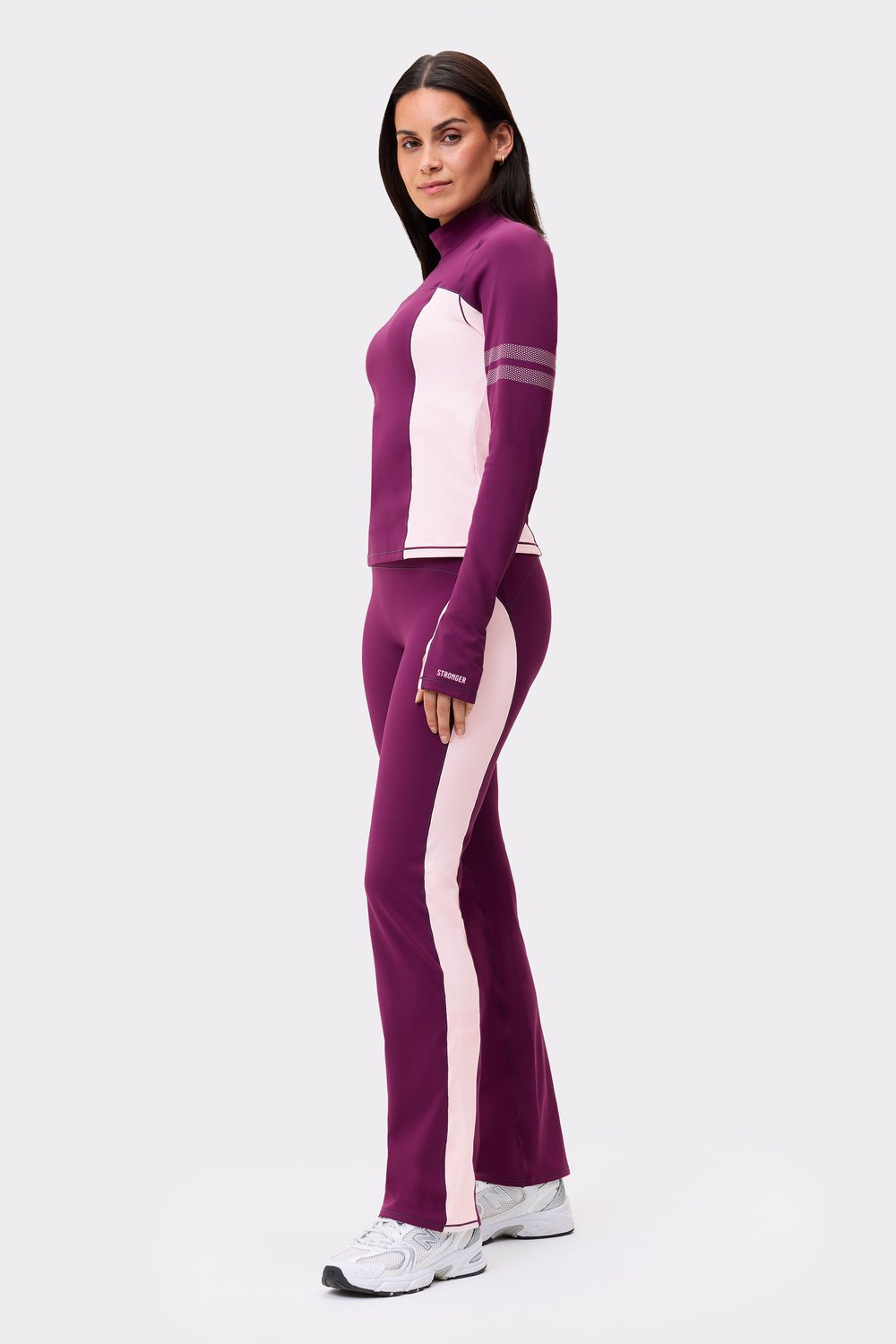 Side view of a model wearing the thermal bootcut pants in aubergine purple and matching top from Stronger.