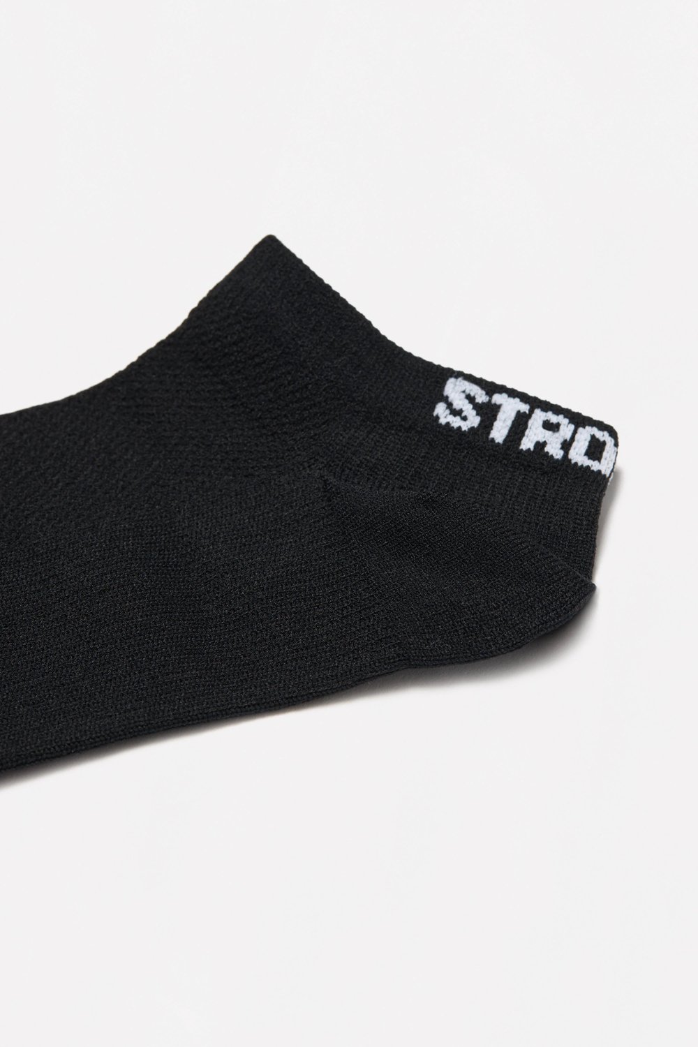 Close-up of the black Sporty Socks from stronger, showing the knitted ankle design and white logotype at the back.