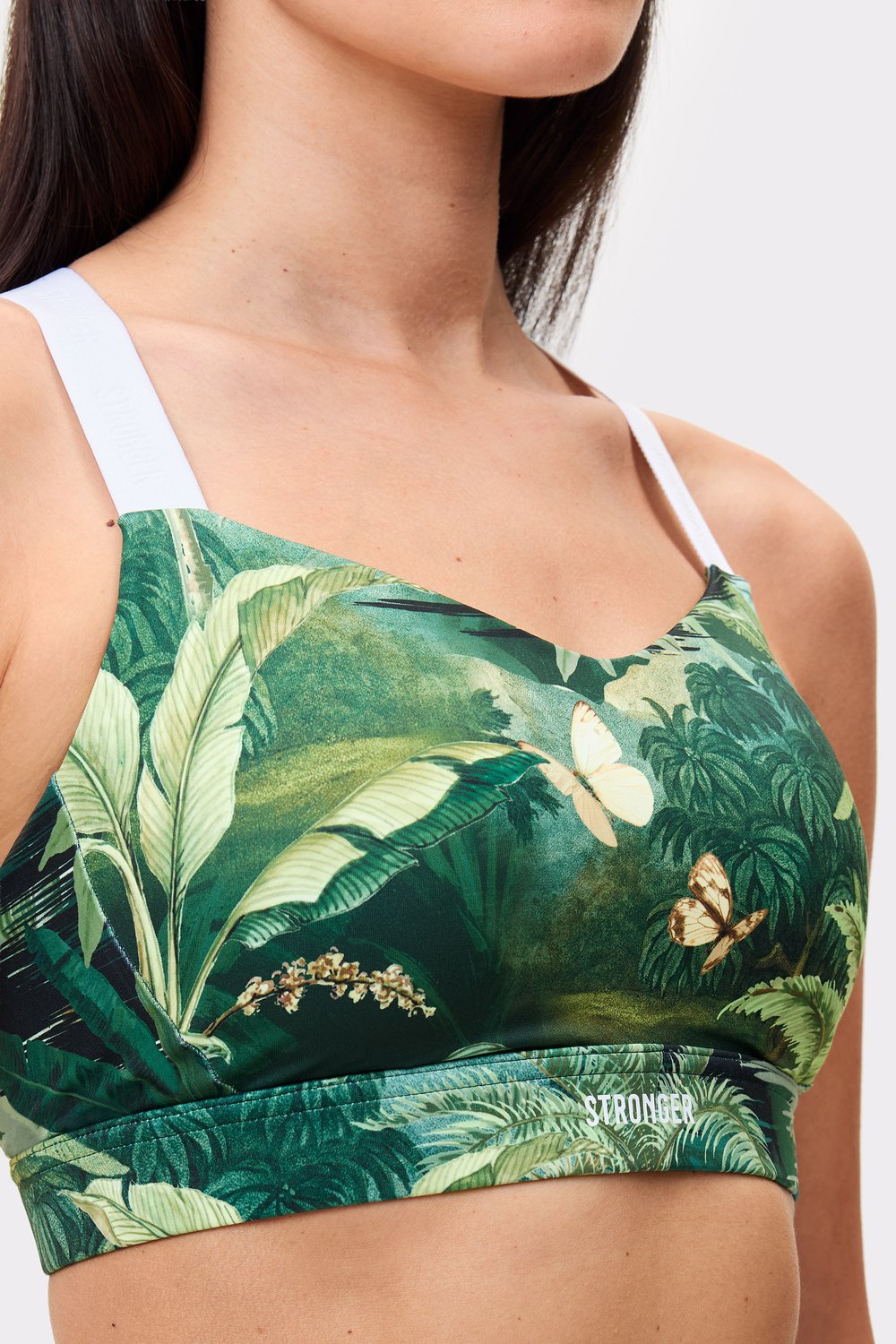 Nahaufnahme eines Models im grünen Power Sports Bra mit Tropical Leaves-Print und weißen Trägern von Stronger.