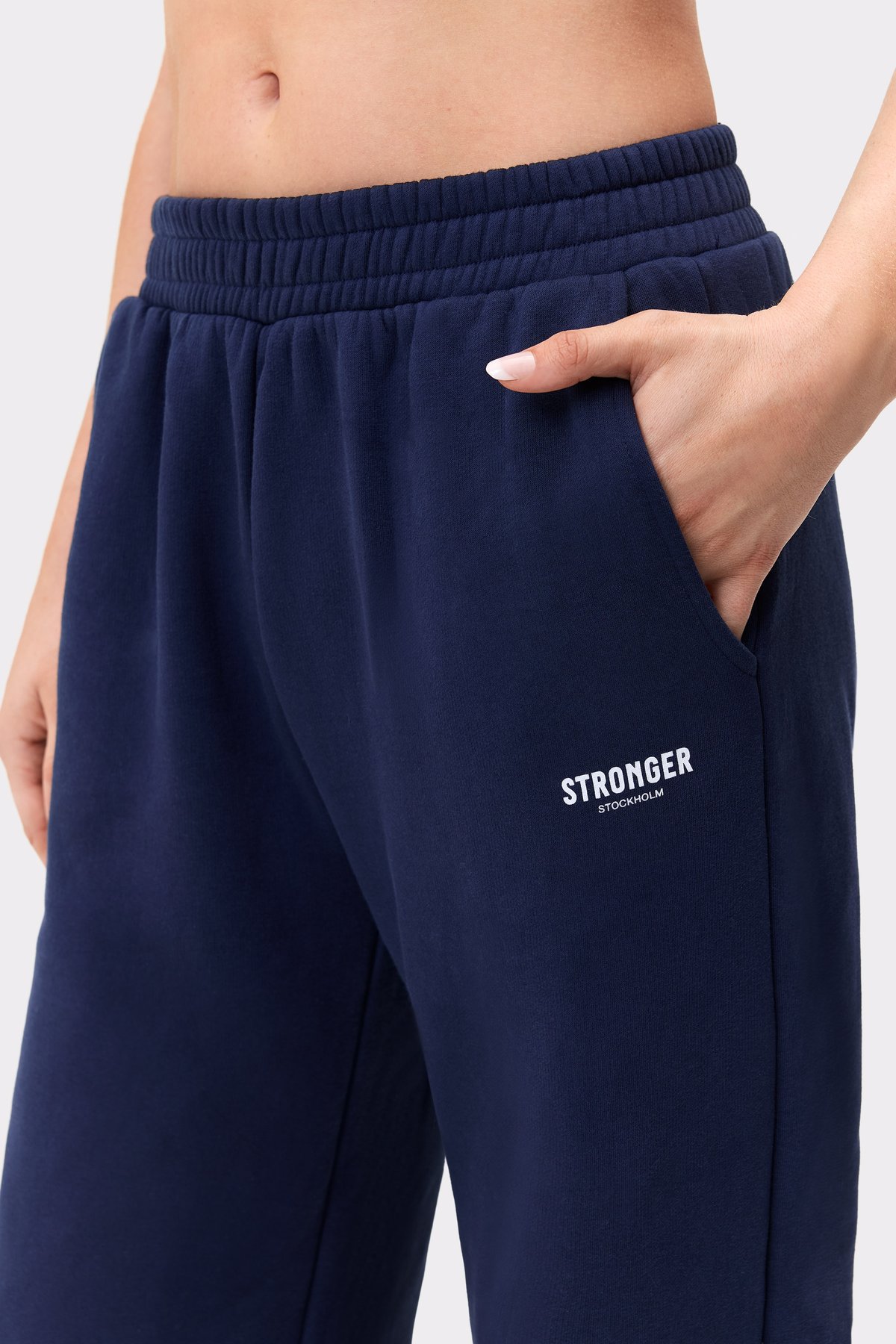 Nahaufnahme der dunkelblauen Relaxed Wide Sweatpants von Stronger mit elastischem Bund, Seitentasche und gesticktem Logo.