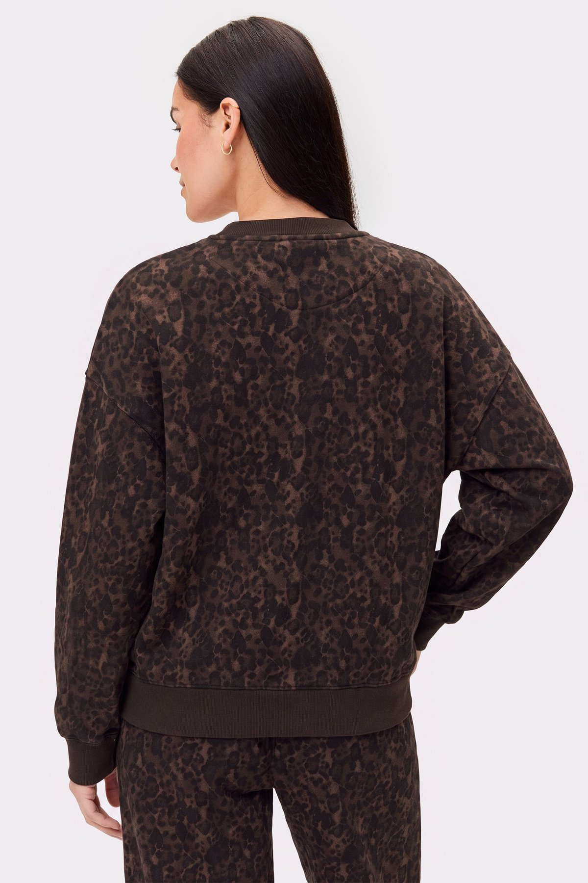 Back view of a model wearing the loose-fit Relaxed Sweatshirt in Dark Leo from Stronger, featuring a cozy dark leopard print.