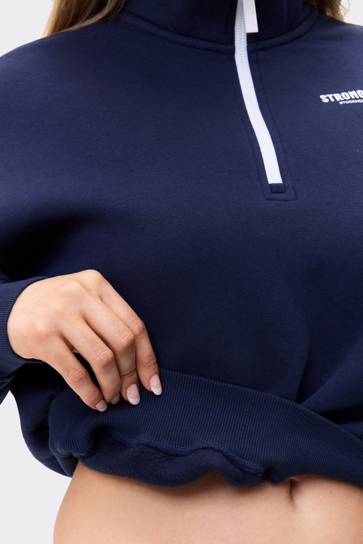 Nahaufnahme des dunkelblauen Half Zip Sweatshirts von Stronger mit dem gerippten Saum und Reißverschlussdetail.