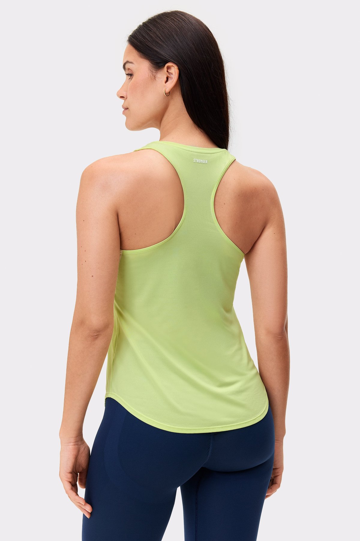 Modell von hinten im limettengrünen Airy Racerback Tank von Stronger, mit Racerback-Design und abgerundetem Saum.