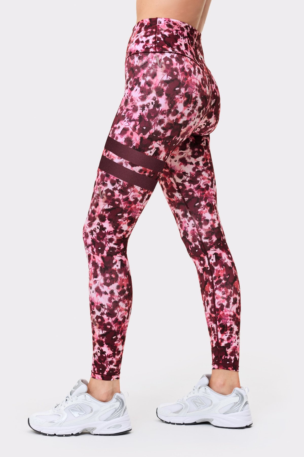 Side view of a model in the Stronger The Signature One Leggings in Autumn Petals, showing the signature lines on the leg.