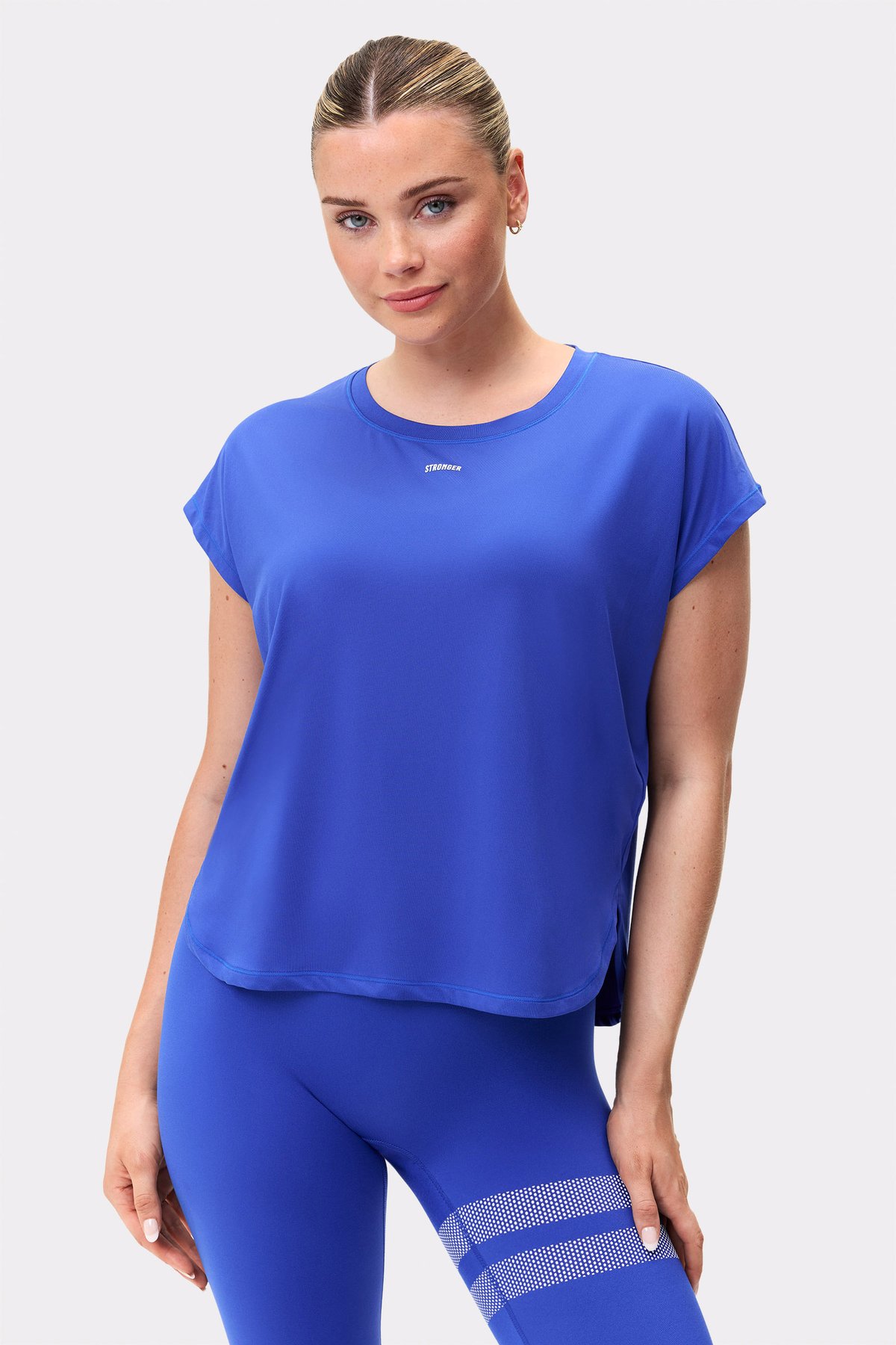 Model trägt das blaue Drop T-shirt von Stronger, ein locker geschnittenes, atmungsaktives Top für hochintensives Training.