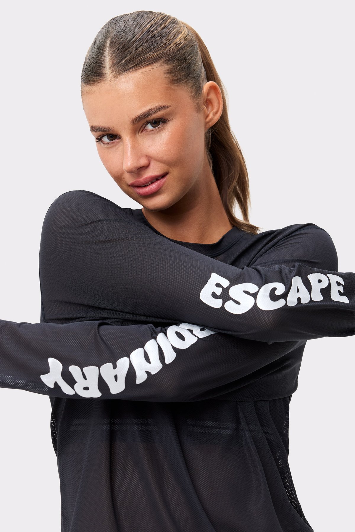 Stronger's black Mesh Running Long Sleeve featuring white ESCAPE ORDINARY text on breathable mesh sleeves.