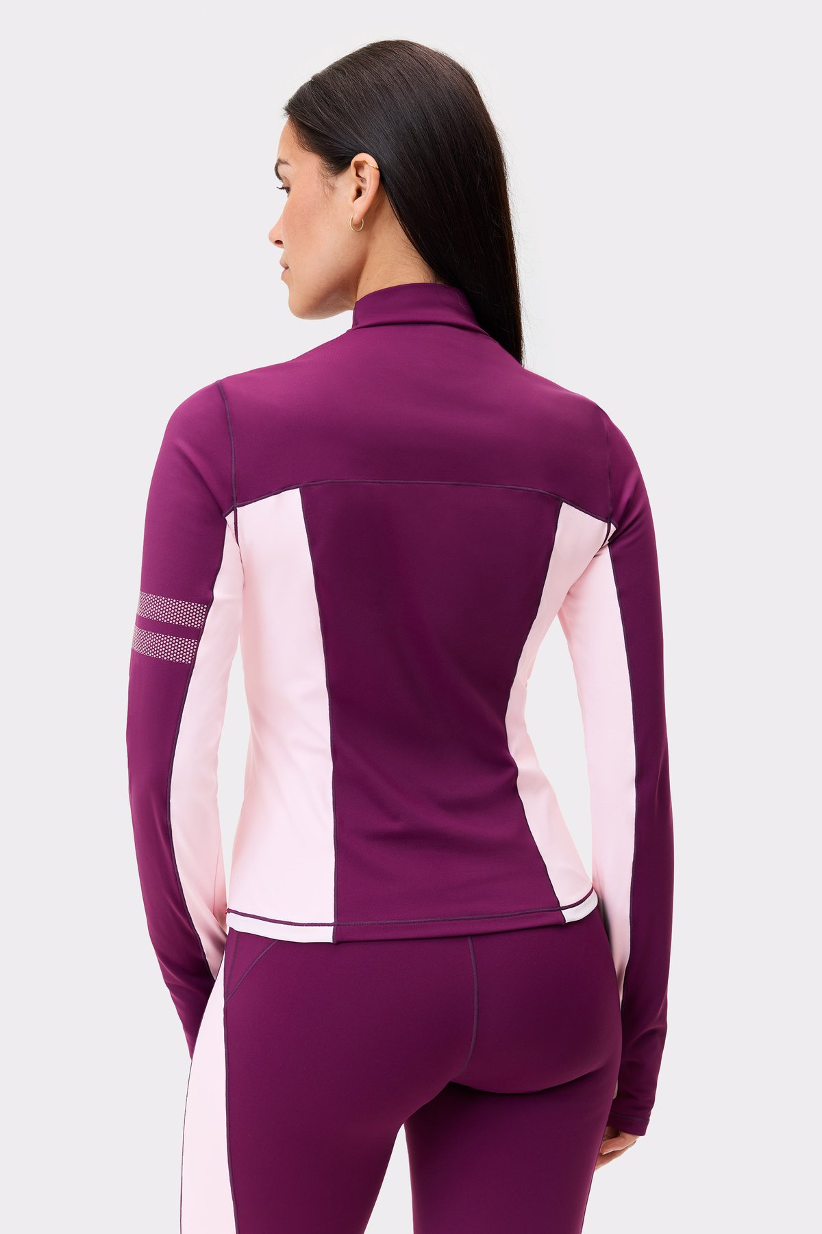 Back view of a model wearing the thermal poloshirt from stronger in deep purple, showing silhouette-enhancing seams.