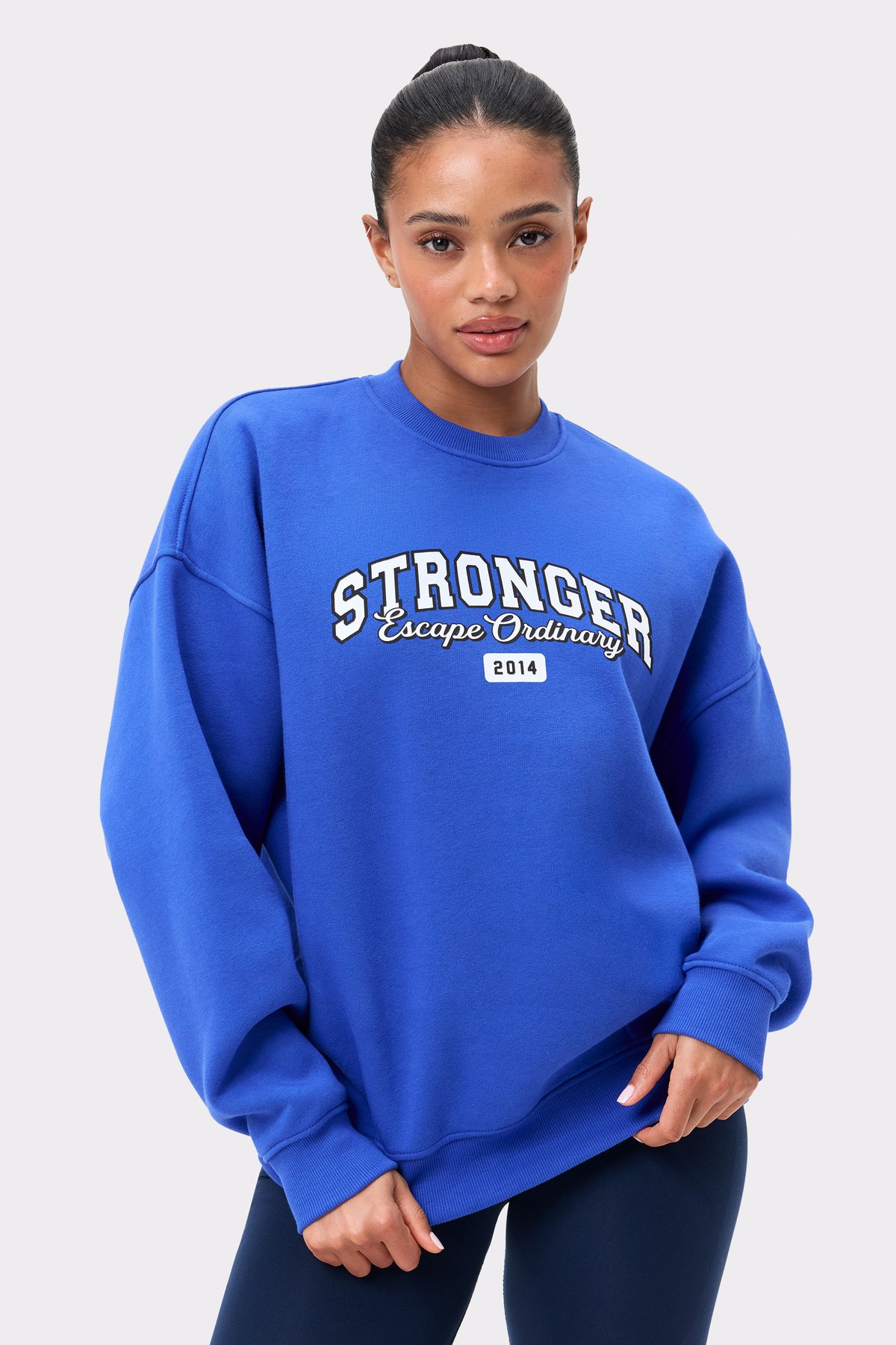 Model in dem blauen Comfy Sweatshirt von Stronger mit Oversized-Passform, angerauter Innenseite und auffälligem Grafikprint.