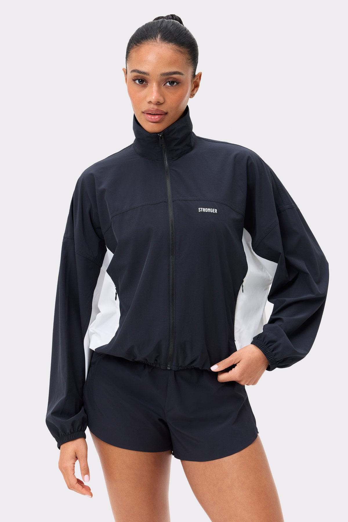 Black and white Breezy Woven Jacket from Stronger, featuring a high neck, full zip, and white side panels.