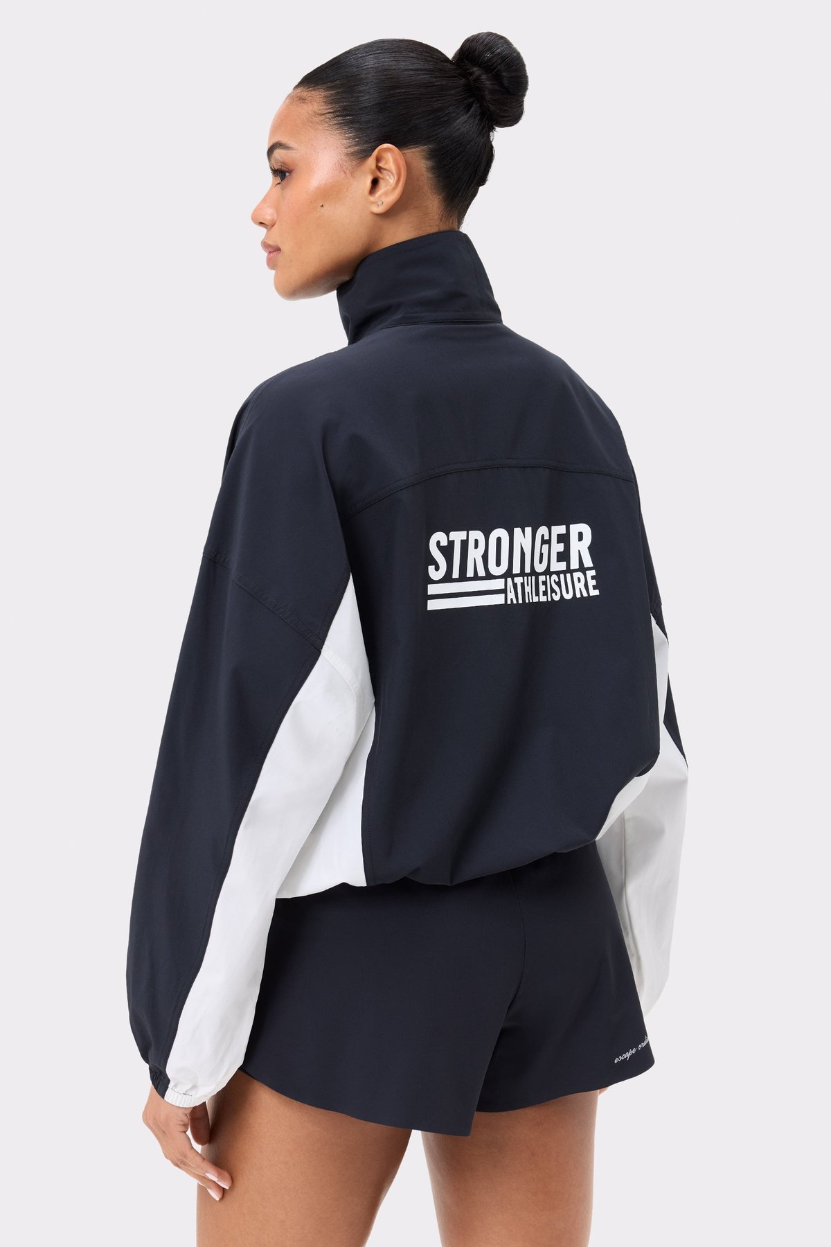 Back view of Stronger's black and white Breezy Woven Jacket, featuring the white logo and breathable woven material.