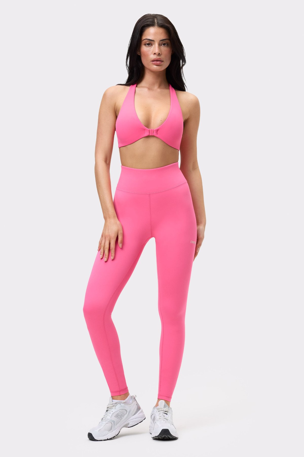 Volledig beeld van een model in de roze Front Closure Sports Bra met bijpassende high-waisted legging van Stronger.
