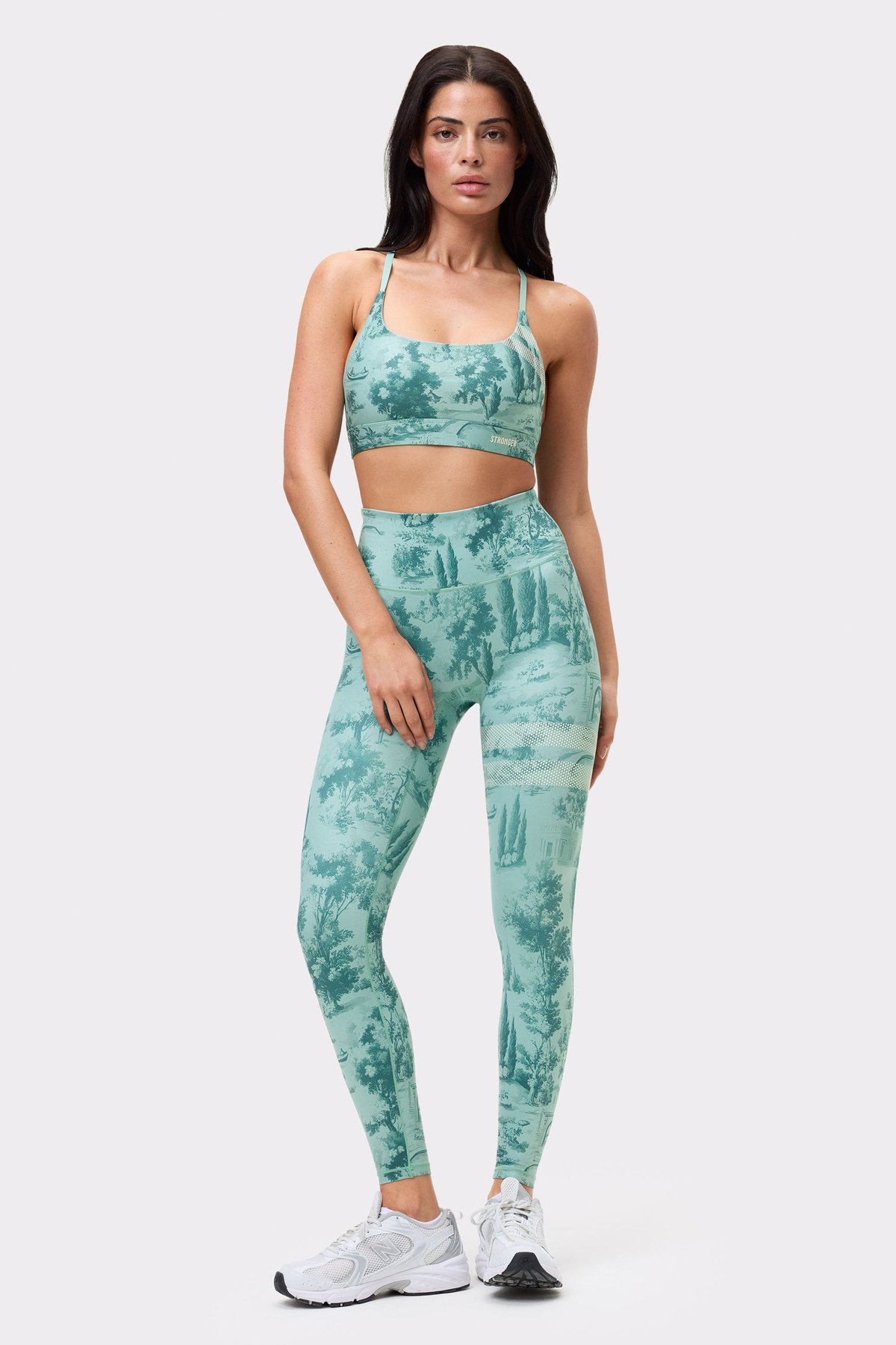 Vorderansicht eines Models im Signature Printed Strap Sports Bra und passenden Leggings mit hellblauem Toile di Roma-Print.