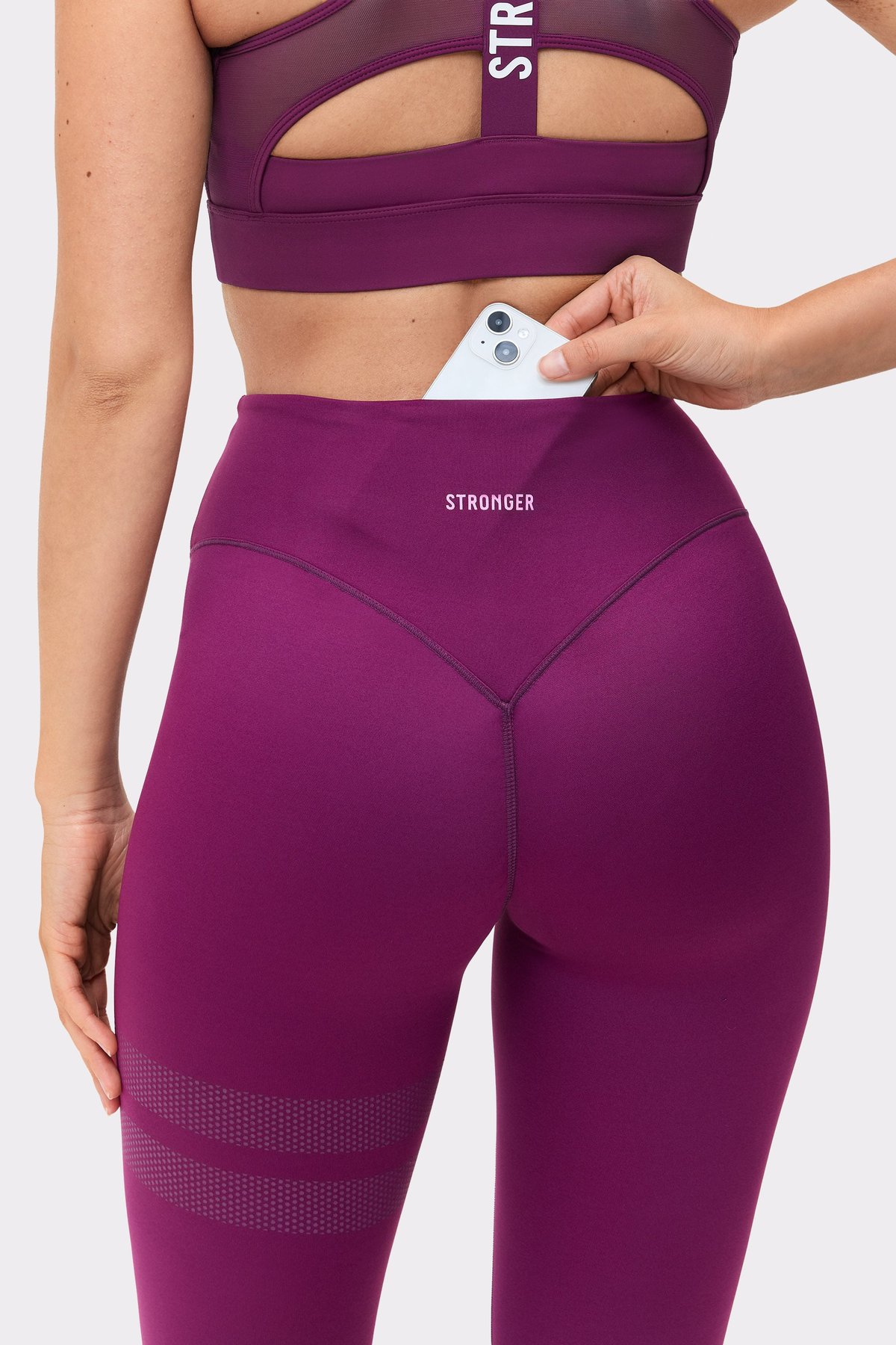 Close-up of a model putting her phone in the back pocket of The Signature One Contour Leggings from stronger.
