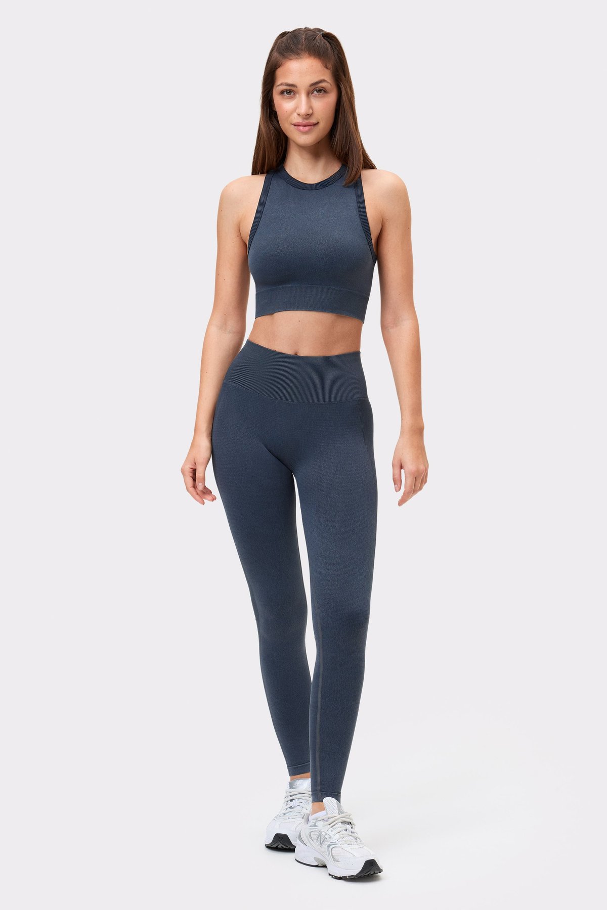 Vorderansicht eines Models mit dem schwarzen Washed seamless high neck bra und passender Leggings von Stronger.