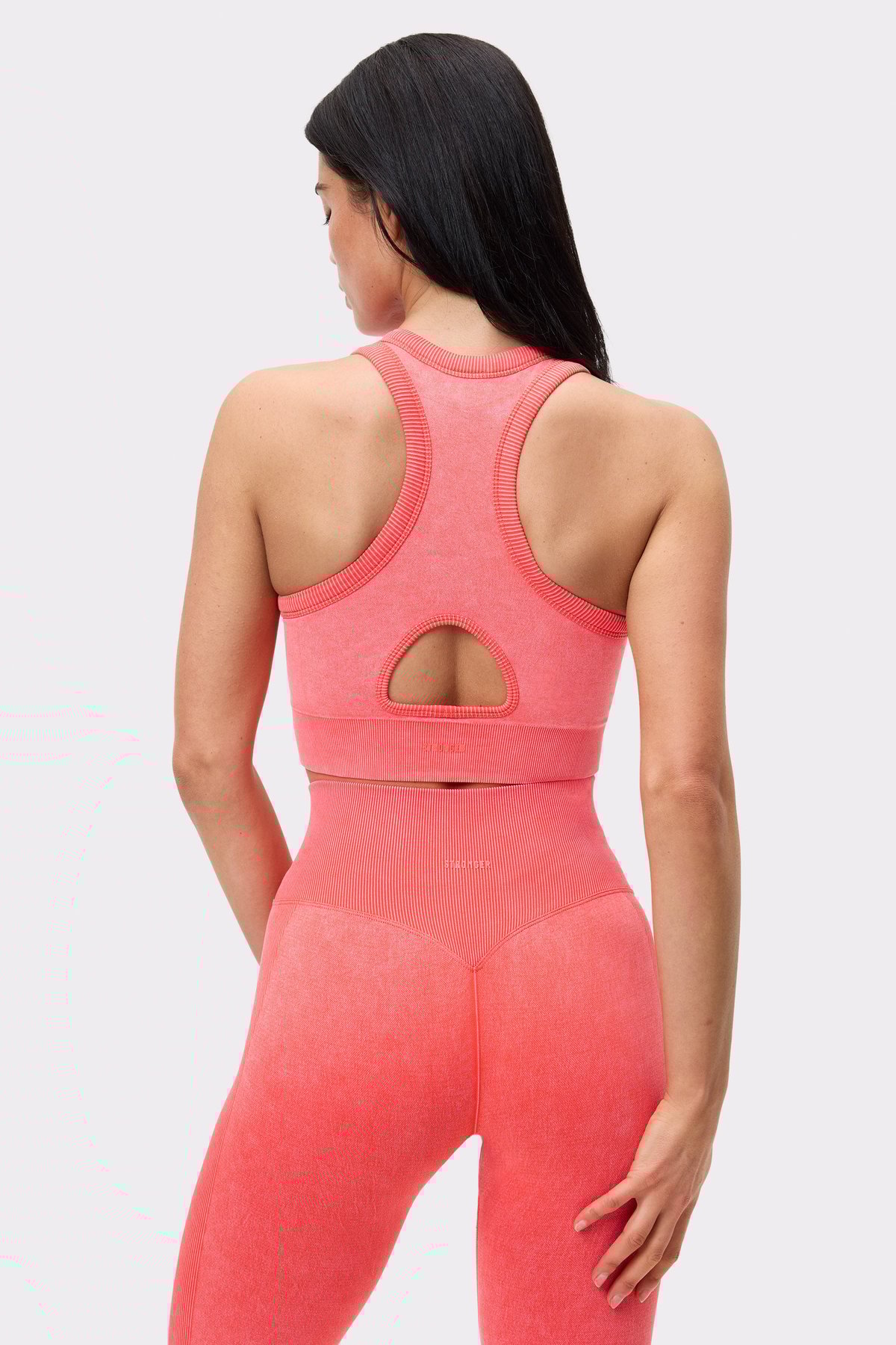 Rückansicht einer Frau im roten Washed seamless high neck bra von Stronger mit Keyhole- und Racerback-Design.
