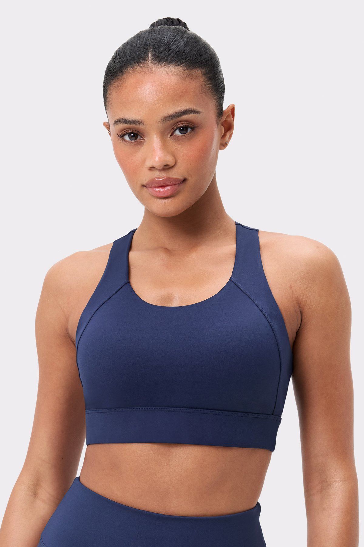 Model in dem dunkelblauen Bounce Sports Bra von Stronger mit breiten Trägern und starkem Halt für das Training.