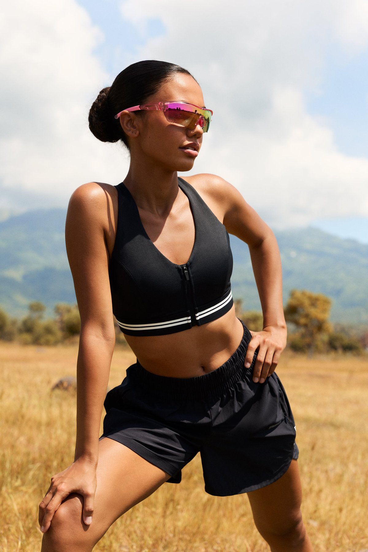 Stronger black Signature Logo Zip Sports Bra featuring a front zipper and white stripes, worn by a model outdoors.