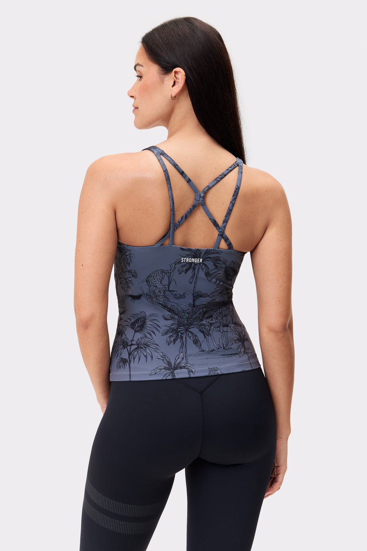 Modell trägt das schmale, verkürzte Stronger Signature Strappy Tank im Dark Toile-Print mit Trägerdetails am Rücken.