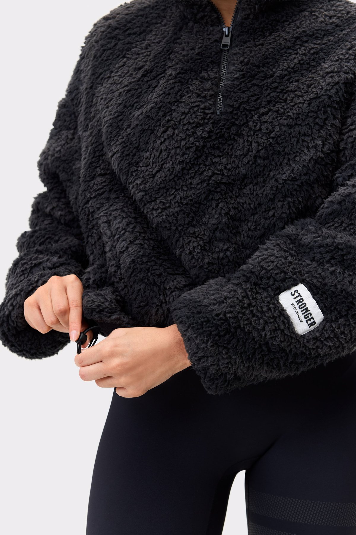 Nahaufnahme der Stronger Pile Half Zip Jacket in Black Zebra mit kuscheliger Fleecetextur und verstellbarem Saum.