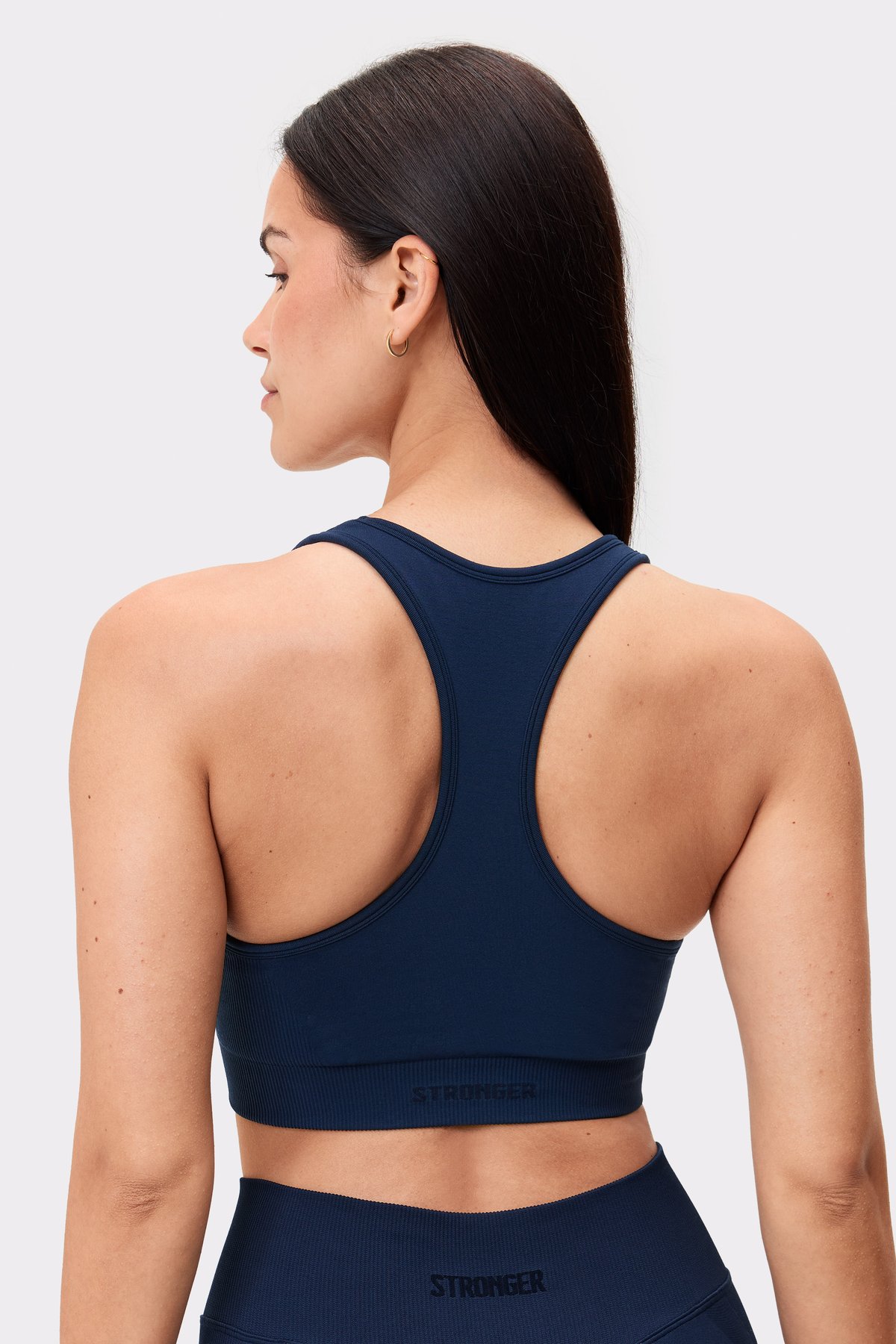 Rückansicht eines Models im dunklen Seamless Contour Sports Bra von Stronger mit Racerback-Design.